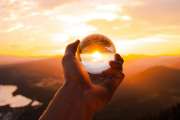 Glaskugel vor Sonnenuntergang in einer Hand