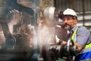 U.S. manufacturing worker at lathe with robotic arm