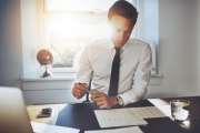 Executive business man working at desk in a classic office while wearing a suit and tie