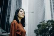 Low angle portrait of confidence young woman standing against highrise city buildings in city