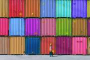 Engineer man with yellow crash helmet and worker west checking cargo freights in front of colorful cargo container stacks in shipping port