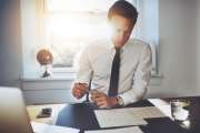 Executive business man working at desk in a classic office while wearing a suit and tie