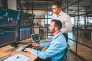 Two successful trader in formalwear working together in office, looking at screen, checking global currency index on fund exchange