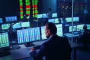 Professional Financial Data Analysts Working in a Modern Monitoring Office with Live Analytics Feed on a Big Digital Screen. Monitoring Room with Finance Specialists Sit in Front of Computers.
