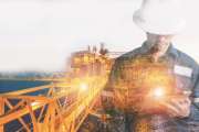 Double exposure of Engineer or Technician man with safety helmet operated platform or plant by using tablet with offshore oil and gas platform background for oil and gas business concept