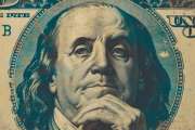 An aged dollar bill with a portrait of Benjamin Franklin, featuring notable wear and aged spots, highlighting its historical significance.
