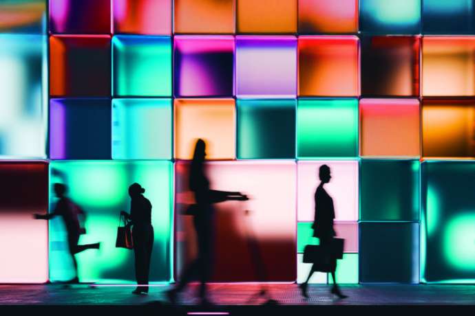 Night render of a building made of glowing cubes, people walking past