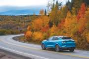 Car cruising along a winding road, surrounded by vibrant autumn trees showcasing stunning fall colors