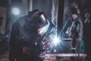 Man is working at metal factory, he is welding a piece of rail using special tools.
