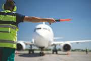 Important signal. Back view of airport worker meeting aircraft and showing right position for landing