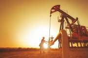 Oil worker is checking the pump near oil derrick on the sunset background.