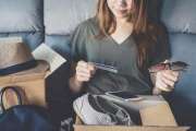 young woman received online shopping parcel opening boxes and buying fashion items by using credit card