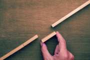 A hand places a wooden block to connect two broken paths representing problem solving, bridging gaps, and overcoming obstacles for progress and personal development