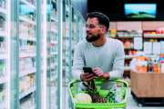 Shot of a young man using a smartphone while shopping in a grocery store.