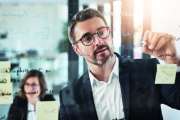 Shot of a mature businessman presenting notes on a glass wall to his colleague in an office