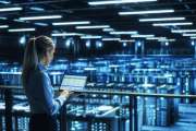 Data Center Female IT Specialist Uses Laptop Computer. Cloud Computing Server Farm with IT Engineer Monitoring Statistic, Maintenance Control. Information Technology of Fintech, e-Business.