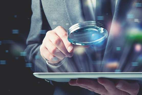 Businessman examines an infected tablet with a magnifying glass. Concept of internet security