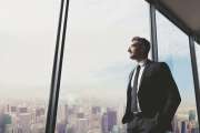 Shot of a handsome mature man looking out from a large window in the office