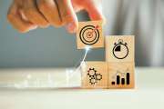 Wood block stacking arranged by a businessman's hand, highlighting the icon of a business strategy and Action plan. Ample copy space for customized content.