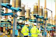Engineers men in warm clothes use digital tablet computer discuss work walking against power electric substation.