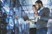 Male IT Specialist Holds Laptop and Discusses Work with Female Server Technician. They're Standing in Data Center, Rack Server Cabinet with Cloud Server Icon and Visualization.