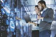 Male IT Specialist Holds Laptop and Discusses Work with Female Server Technician. They're Standing in Data Center, Rack Server Cabinet with Cloud Server Icon and Visualization.