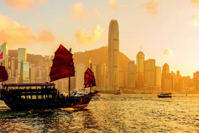 Chinese wooden red sails ship in Hong Kong Victoria harbor at sunset time