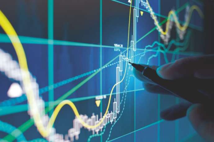 A business person tracking the technical movement of a stock chart on a computer screen.