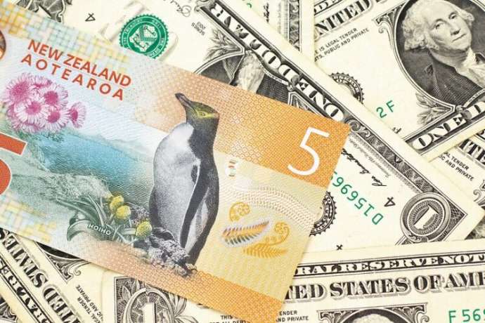 A close up image of a New Zealand five dollar bill with United States one dollar bills in macro