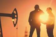 oil production. two silhouette workers work as a team next to an oil pump. business oil production production concept. two engineers of the oil and gas industry are sun discussing business plan