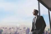 Shot of a handsome mature man looking out from a large window in the office
