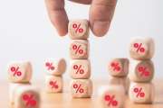 Hand holding and stacking red percentage sign print screen on wooden cube block for interest rate and business profit growth concept.