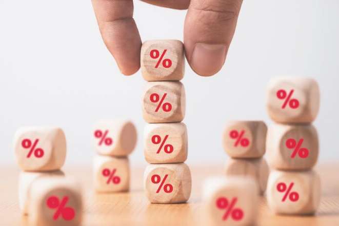 Hand holding and stacking red percentage sign print screen on wooden cube block for interest rate and business profit growth concept.