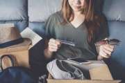 young woman received online shopping parcel opening boxes and buying fashion items by using credit card