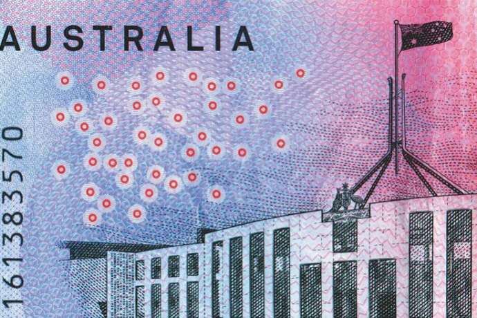Close up of an Australia five dollar note showing a line drawing of parliament house canberra, the text Australia and the number on the bank note